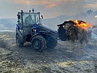 Der Radlader des THW Gießen beräumt brennende Heuballen